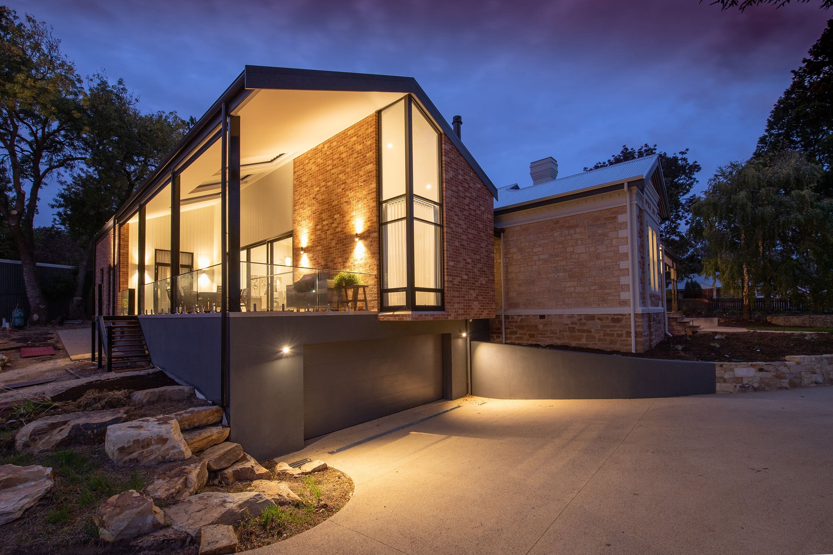 Modern two-storey residence at twilight with warm architectural exterior lighting